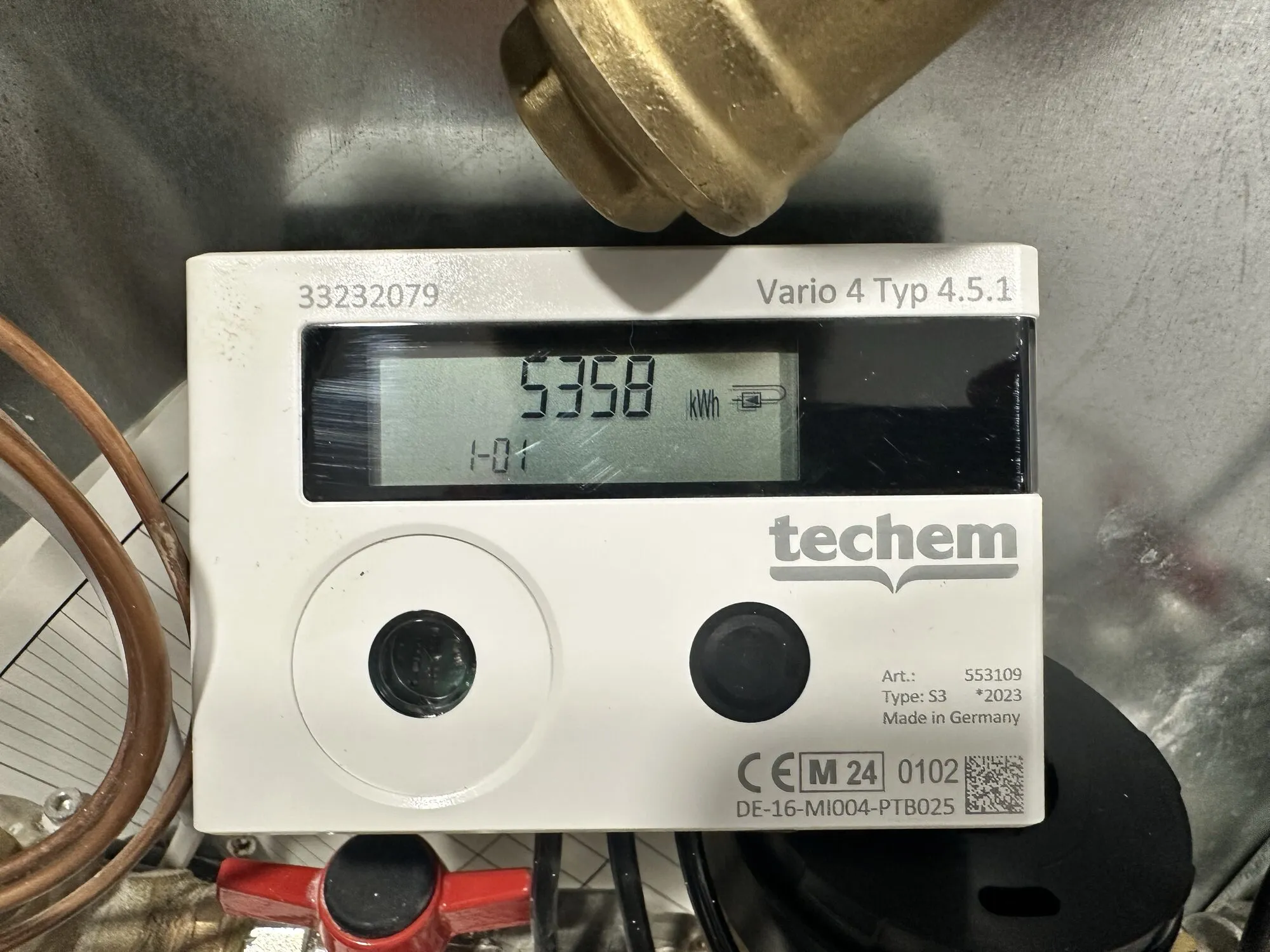 Kalorimetr Techem Vario 4: bílá skříňka s displejem, na kterém svítí 5358 kWh, a kulatým černým tlačítkem vpravo pod ním.