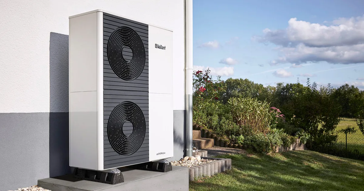 Vysoká venkovní jednotka tepelného čerpadla aroTHERM plus se dvěma ventilátory, instalovaná na betonovém základu u fasády budovy